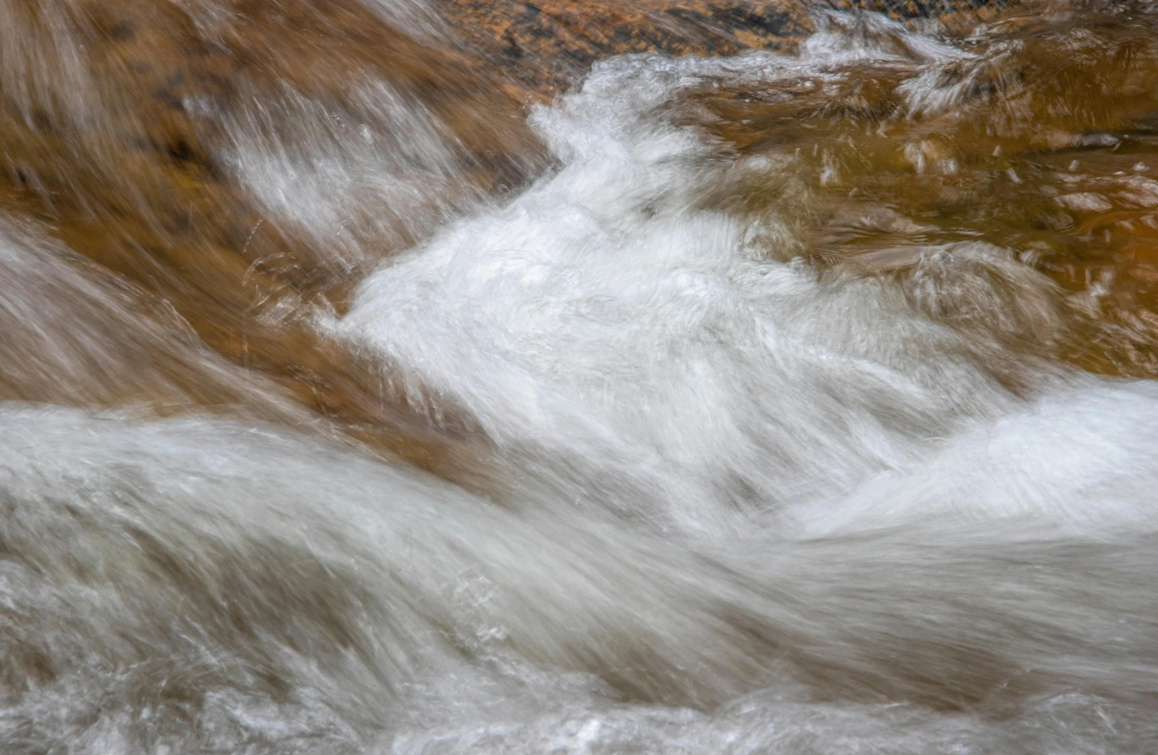 a close up of a stream of water with rocks in the background, inspired by Andreas Gursky, trending on unsplash, lyrical abstraction, browns and whites, unsplash photo contest winner, river rapids, liquid metal