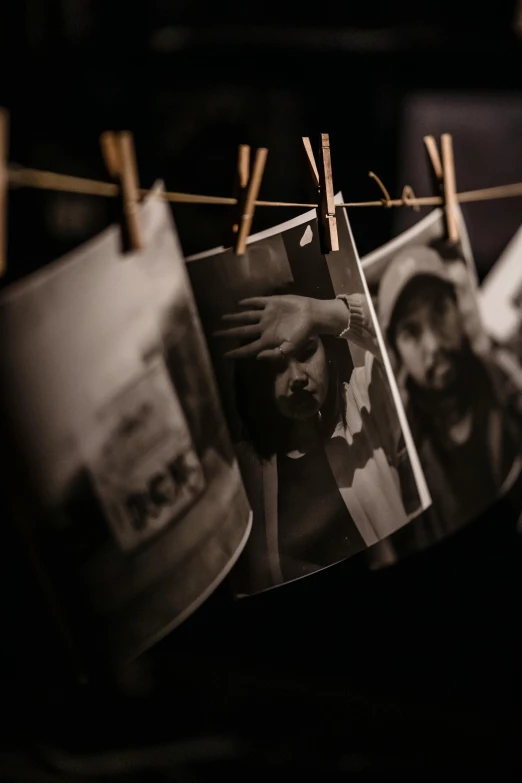 a bunch of pictures hanging on a clothes line, a black and white photo, by Adam Szentpétery, unsplash, movie scene portrait closeup, studio medium format photograph, concert, vintage photograph