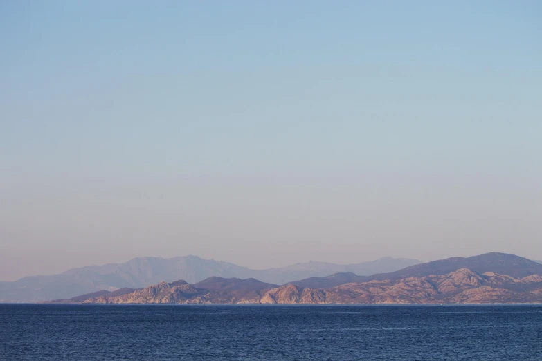 a large body of water with mountains in the background, by Alexis Grimou, cloudless-crear-sky, low quality photo, red sea, muted coloures