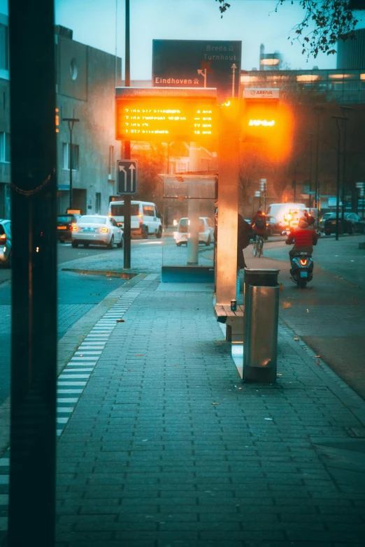 a yellow traffic light sitting on the side of a road, a picture, by Adam Marczyński, dark city bus stop, orange neon, during dawn, bustling city