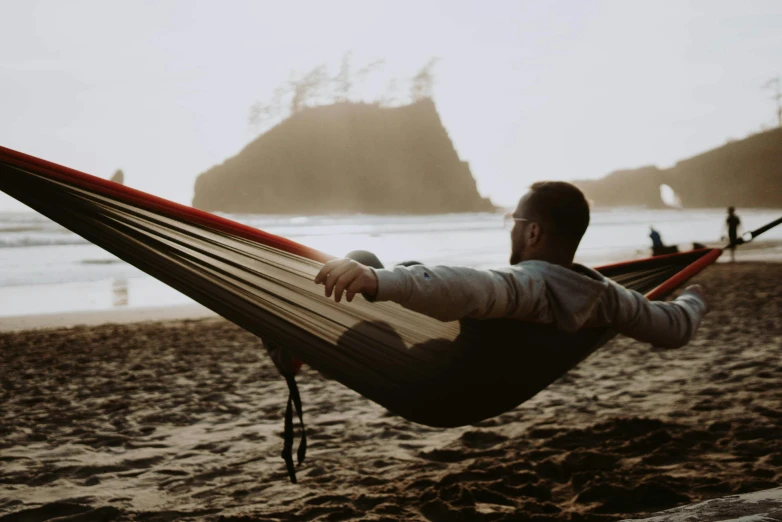 a man laying in a hammock on the beach, by Jessie Algie, pexels contest winner, pacific northwest, avatar image, camping, profile image