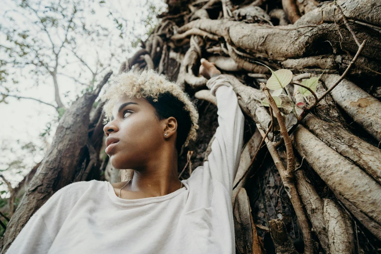 a woman standing in front of a tree, by Carey Morris, pexels contest winner, afrofuturism, short curly blonde haired girl, androgynous male, young woman looking up, side portrait rugged girl