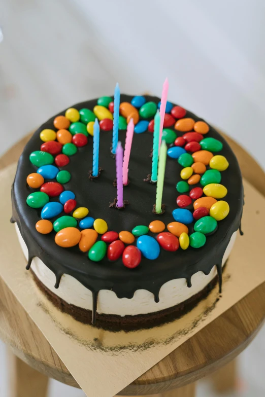 a birthday cake sitting on top of a wooden table, jellybeans, black main color, medium, full product shot