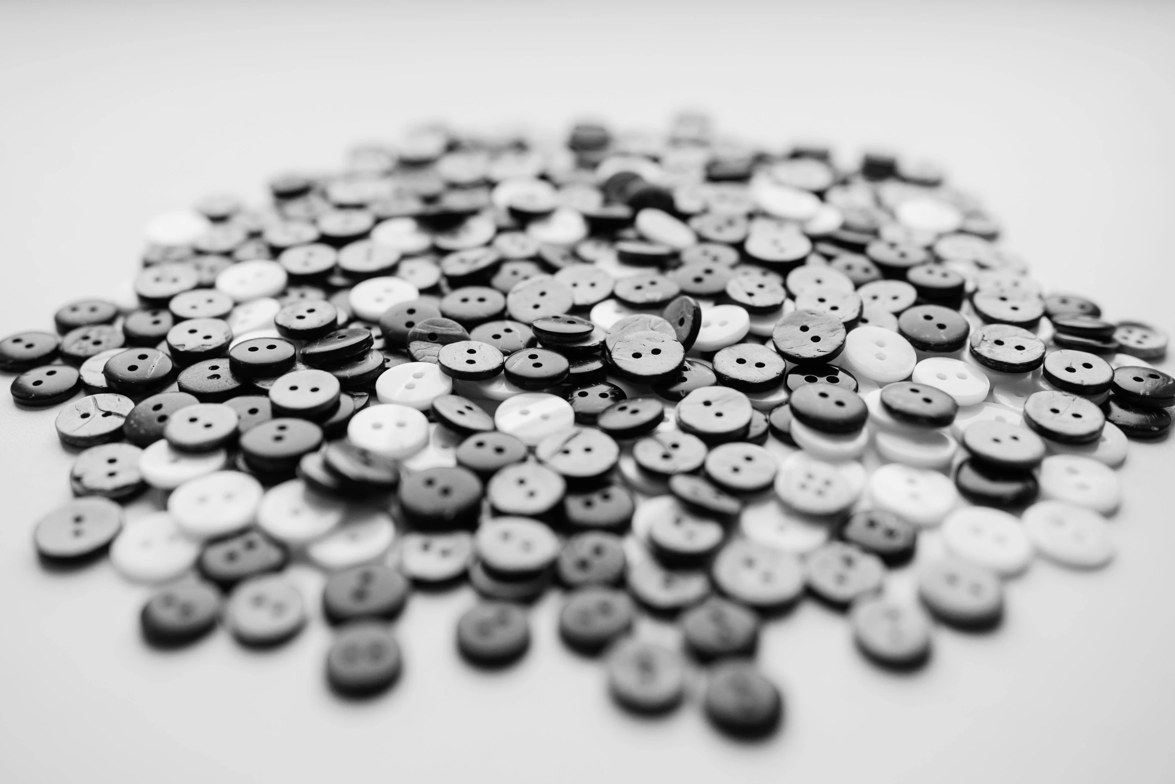 a pile of buttons sitting on top of a table, a black and white photo, by Karl Buesgen, unsplash, miniature product photo, plastic ceramic material, detailed photo 8 k, pixel sort