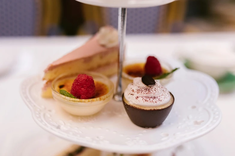 a white plate topped with desserts on top of a table, tea cup, thumbnail, up-close