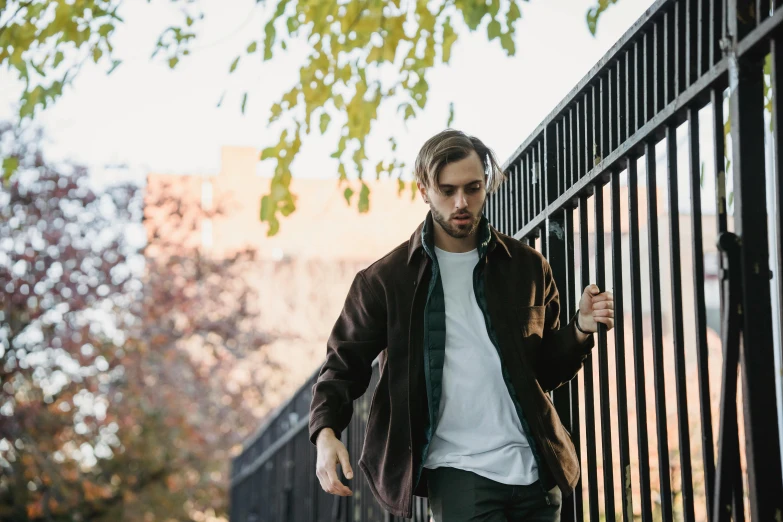 a man riding a skateboard down a sidewalk, a portrait, unsplash, standing astride a gate, brown clothes, felix englund style, looking off to the side