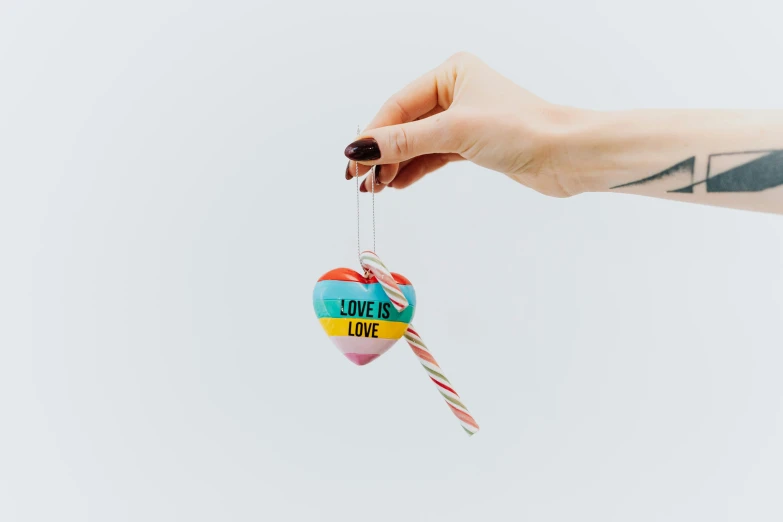 a woman's hand holding a lollipop lollipop lollipop lollipop lollipop lollipop lollipop, inspired by Okuda Gensō, unsplash, graffiti, on a candle holder, set against a white background, hanging rope, glass-cast heart