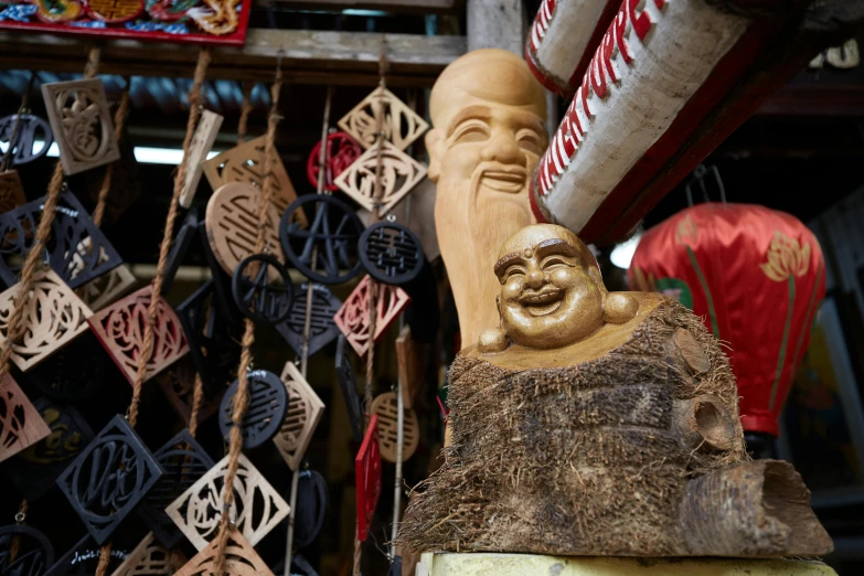 a statue of a laughing buddha sitting on top of a tree stump, a portrait, trending on unsplash, cloisonnism, market stalls, masks on wires, inside an old magical shop, fan favorite