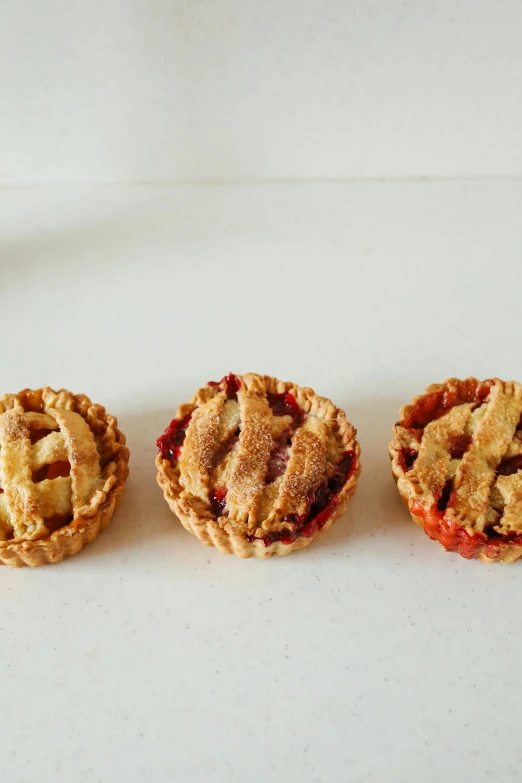 three mini pies sitting next to each other on a table, 3 - piece, petite, reds), peach