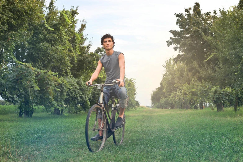 a man riding a bike through a lush green field, an album cover, inspired by John Luke, pexels contest winner, realism, attractive man, bicycles, thin young male, azimov