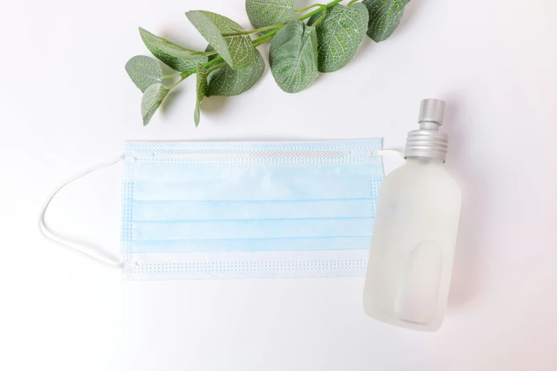 a bottle of hand sanitizer next to a face mask, shutterstock, eucalyptus, without text, product view, grey