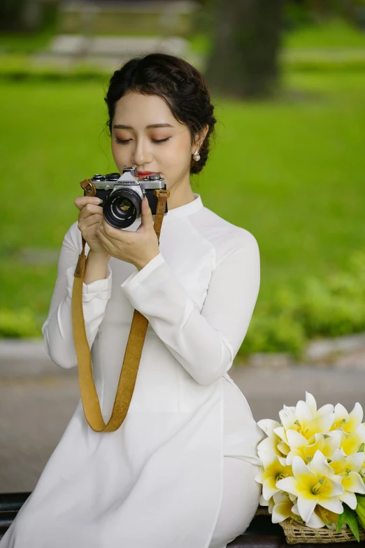 a woman sitting on a bench taking a picture with a camera, inspired by Ruth Jên, carrying flowers, wearing white clothes, dang my linh, professional photo-n 3