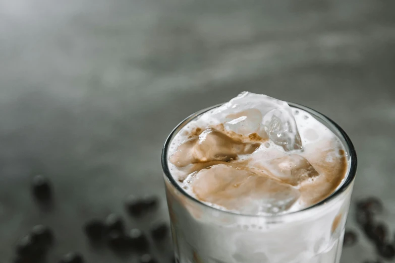 a glass of iced coffee sitting on top of a table, trending on pexels, background image, grey, ice cubes, thumbnail