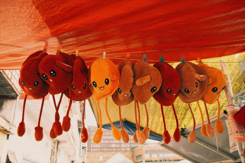 a group of stuffed animals hanging from a tent, by Julia Pishtar, pexels contest winner, furry art, dark oranges reds and yellows, kidneys, in a row, orange roof