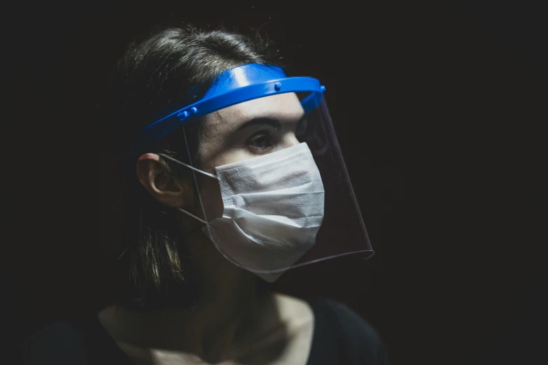 a woman wearing a protective face mask, by Adam Marczyński, pexels, hyperrealism, glowing visor, in front of a black background, people at work, medical