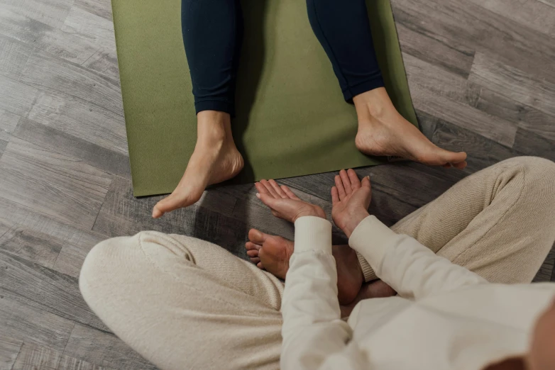 a man and a woman sitting on a yoga mat, a picture, by Carey Morris, trending on pexels, tiny feet, woman holding another woman, sprawled out, upper and lower body