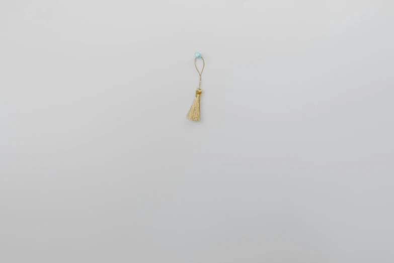 a pair of earrings sitting on top of a table, by Makoto Aida, conceptual art, light grey blue and golden, 1849, tassels, tatsuro kiuchi