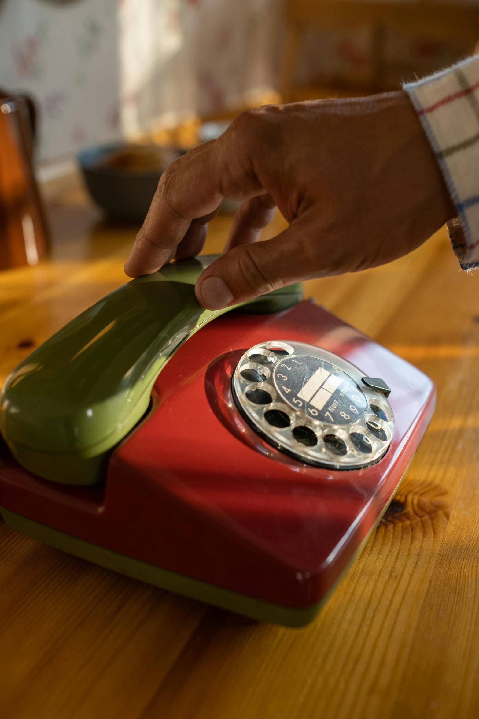 a red and green telephone sitting on top of a wooden table, hands on counter, as well as scratches, from the 7 0 s, bay area