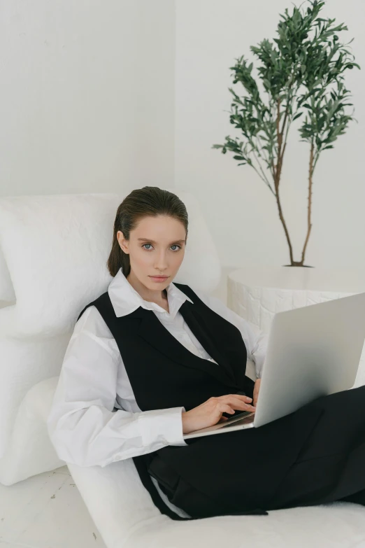 a woman sitting in a chair with a laptop, trending on pexels, white dress shirt, wearing black vest and skirt, wearing white pajamas, human computer