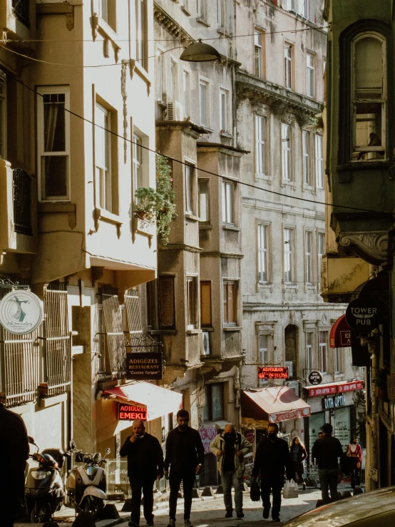 a group of people walking down a street next to tall buildings, by Cafer Bater, pexels contest winner, renaissance, istanbul, storefronts, warm sunlight shining in, a quaint