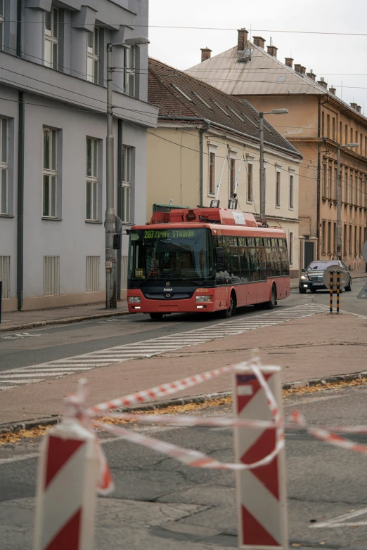 a red bus driving down a street next to tall buildings, reddit, in empty!!!! legnica, emergency countermeasures, 🚿🗝📝