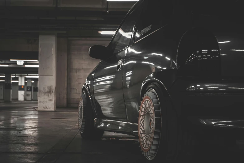 a black car parked in a parking garage, unsplash, hyperrealism, slick tires, alfa romeo project car, 90's photo, low quality footage