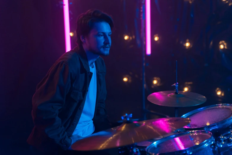 a man sitting in front of a drum set, cinematic pastel lighting, mark edward fischbach, purple scene lighting, **cinematic