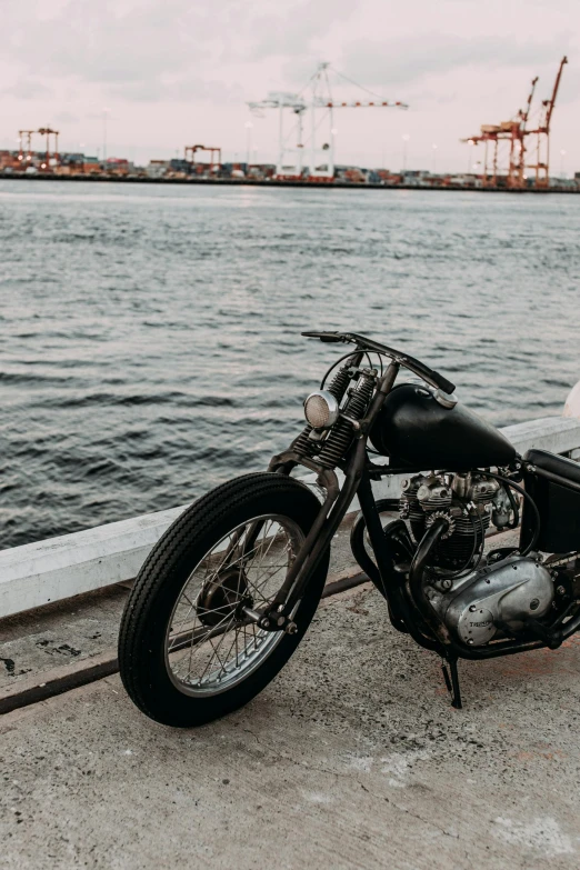 a motorcycle parked next to a body of water, pexels contest winner, restomod, black, low quality photo, steel skin