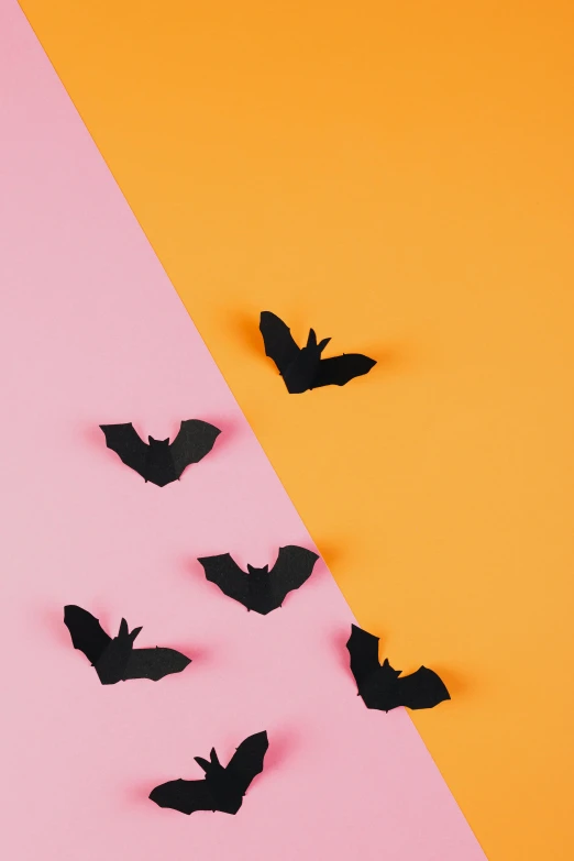 a group of bats on a pink and orange background, trending on pexels, conceptual art, matte black paper, hero shot, on