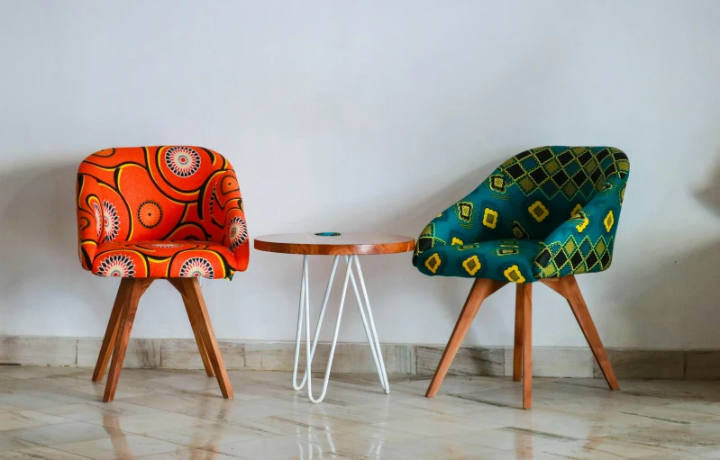 a couple of colorful chairs sitting next to each other, inspired by Afewerk Tekle, trending on unsplash, made of fabric, table, african, commercially ready