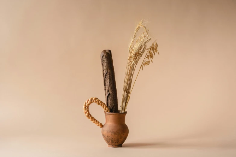 a vase with some dried plants in it, a still life, inspired by Hendrik Gerritsz Pot, unsplash, holding a baguette, bakery, worm brown theme, miniature product photo