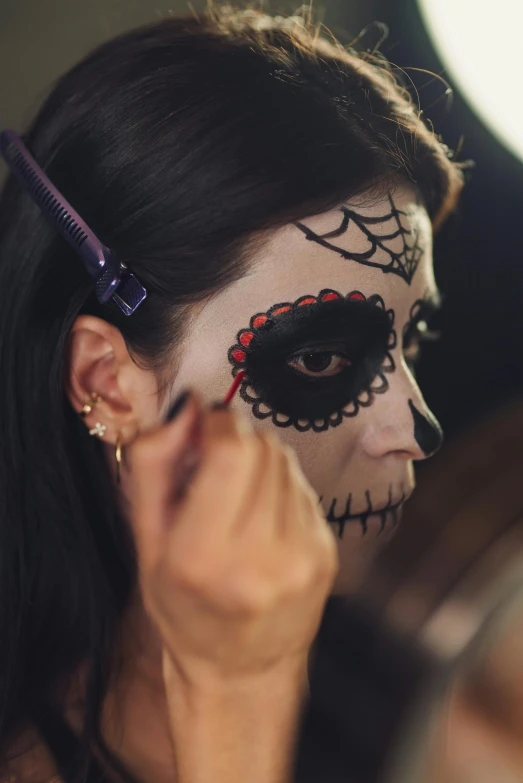 a woman is getting her make up done, lowbrow, skull face paint, promo image, close - up profile face, mexican