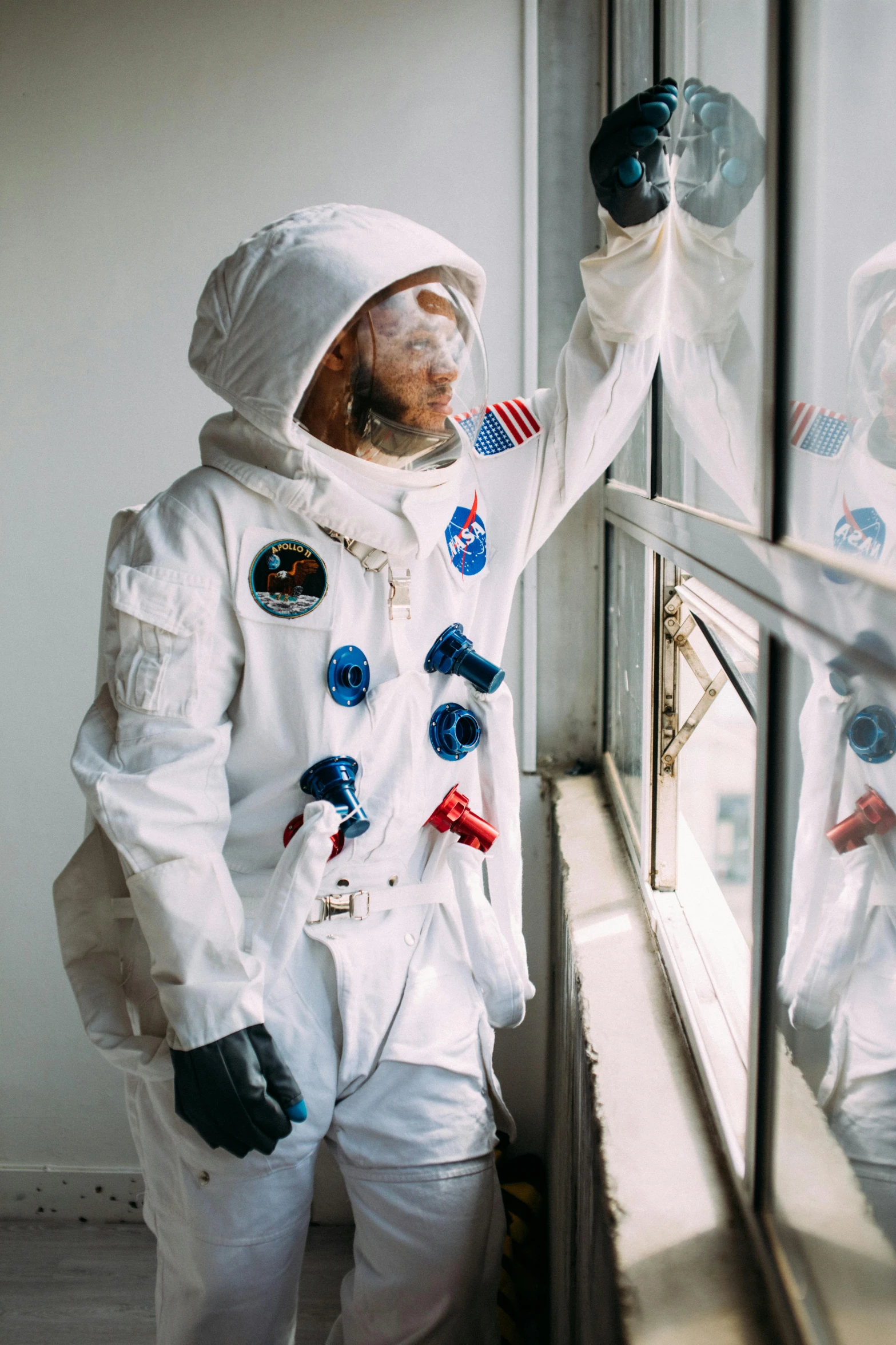 a couple of people that are standing in front of a window, inspired by Alan Bean, pexels contest winner, full costume, one man, white uniform, rubber suit