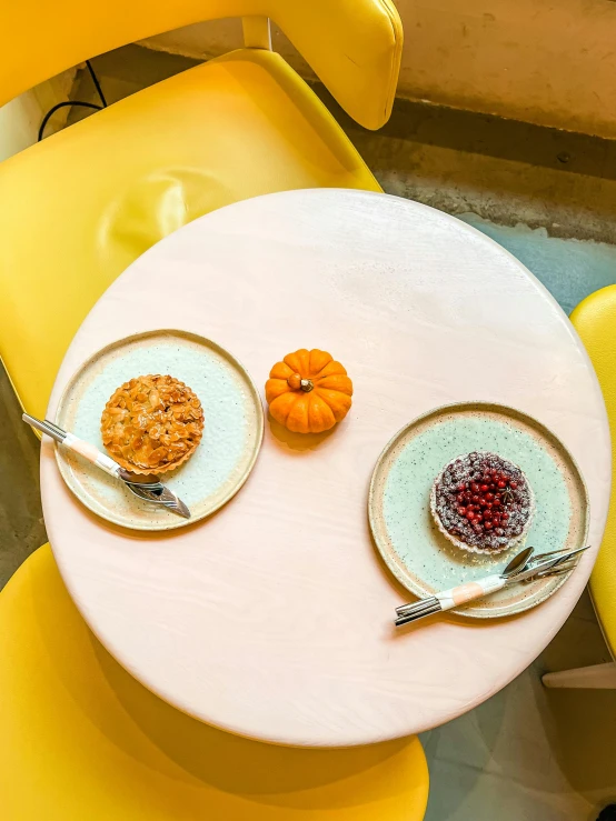 a table with two plates of food on it, bakery, november, on a yellow canva, round format
