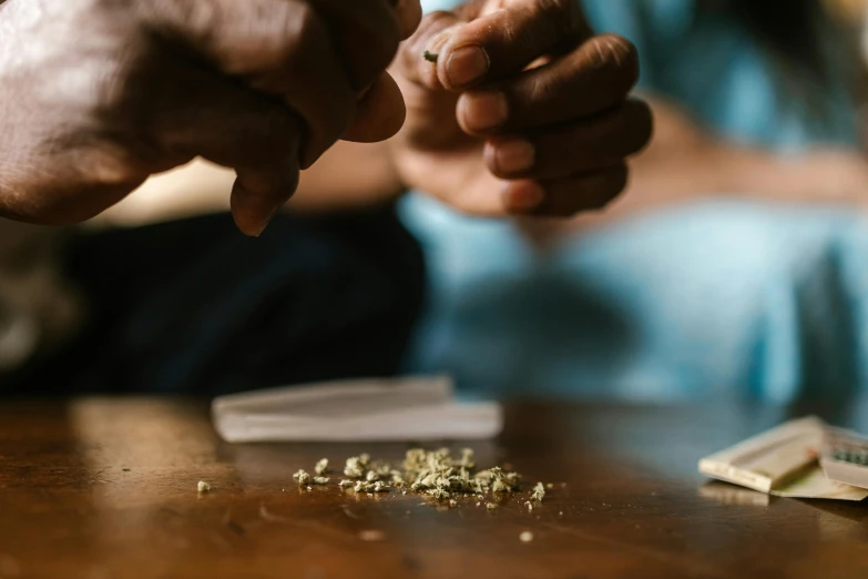 a close up of a person holding a cigarette, pot plants, on a table, weed, thumbnail