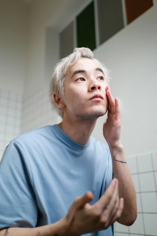 a man shaving his face in a bathroom, by Jang Seung-eop, pale hair, holding his hands up to his face, chiseled jawline, 21 years old