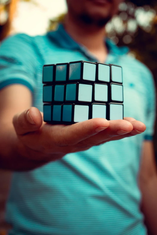 a man holding a rubik cube in his hand, inspired by Ernő Rubik, unsplash, black and cyan color scheme, 2 5 6 x 2 5 6 pixels, square shapes, paul barson