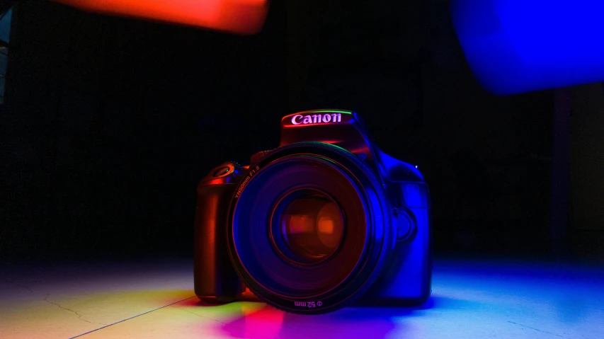 a close up of a camera on a table, inspired by Elsa Bleda, unsplash contest winner, art photography, blue and red glowing lights, rainbow caustic lighting, taken with a canon dslr camera, red and blue black light