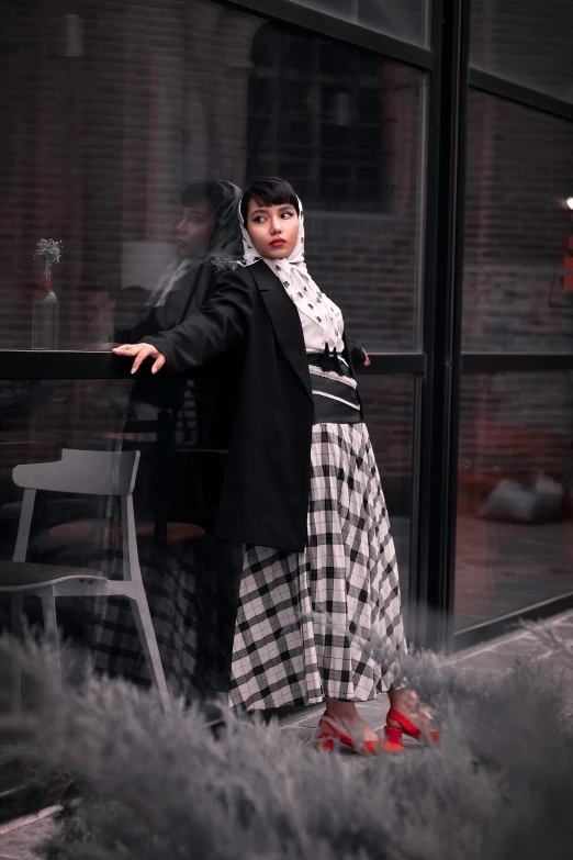 a woman standing in front of a window next to a chair, inspired by Bernardino Mei, pexels contest winner, wearing jacket and skirt, on a checkered floor, zaha hadi, plus size