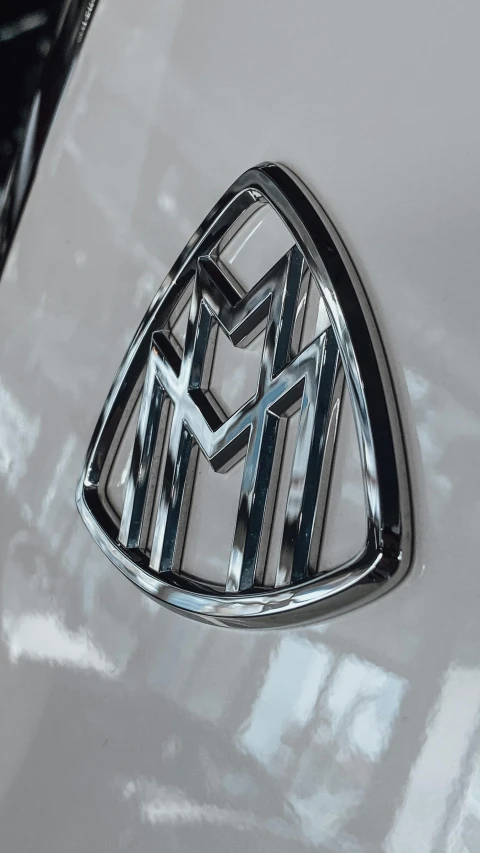 a close up of a badge on a car, by Matt Cavotta, instagram, modernism, black gotic letter m, 15081959 21121991 01012000 4k, made of nanomaterials, white metallic