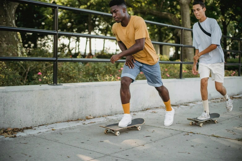 two young men riding skateboards down a sidewalk, trending on pexels, gold soccer shorts, essence, college students, harriet tubman skateboarding