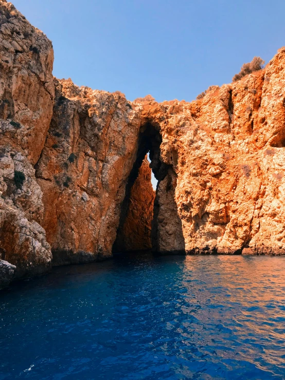 a cave in the middle of a body of water, greek nose, rich deep colours, thumbnail, no crop