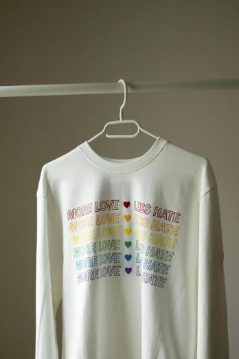 a white shirt on a hanger in a room, rainbow accents, wearing sweatshirt, love hate love, mixed medias