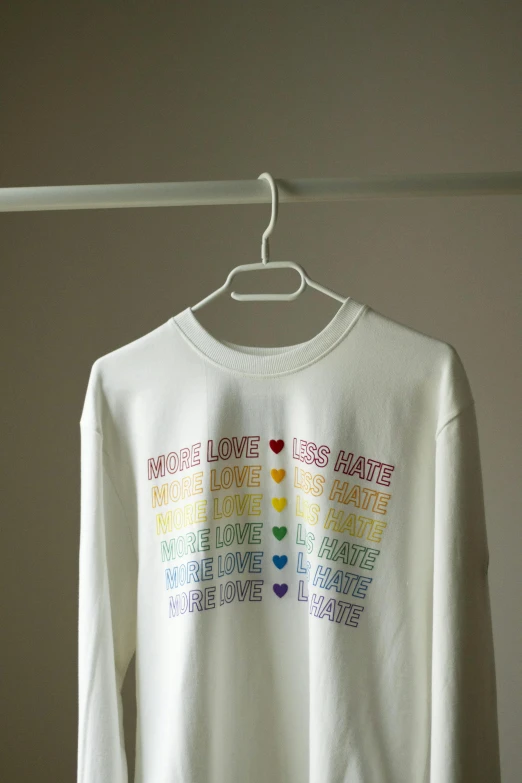 a white shirt on a hanger in a room, rainbow accents, wearing sweatshirt, love hate love, mixed medias