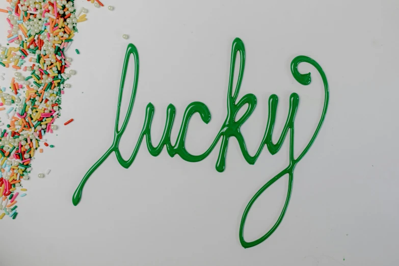 a sign that says lucky surrounded by sprinkles, skin painted with green, paper quilling, ffffound, vinyl on glazing