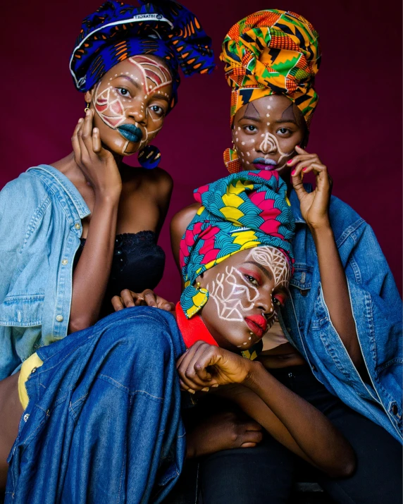 a couple of women sitting next to each other, an album cover, by Ingrida Kadaka, trending on unsplash, afrofuturism, facepaint, bandanas, three women, ( colorful )