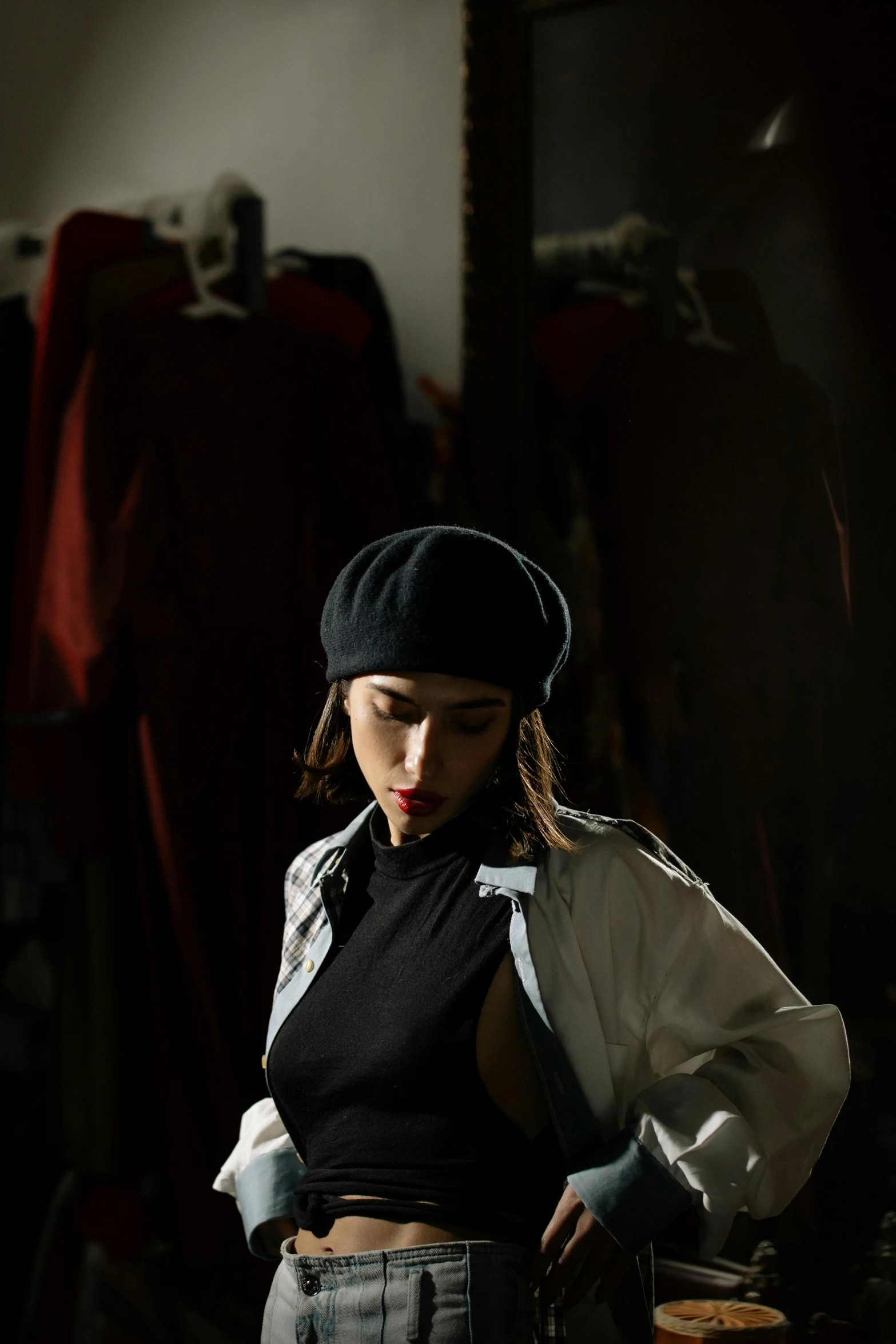 a woman standing in a dark room with her hands on her hips, a portrait, inspired by Horace Vernet, trending on pexels, black beret, marvelous designer, profile pic, streetwear