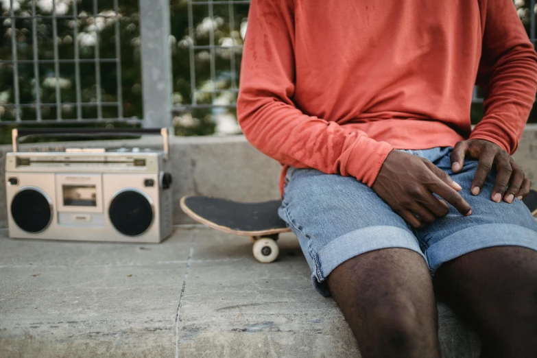 a man sitting on a ledge with a skateboard, trending on pexels, ghetto blaster, dressed in a top and shorts, warm coloured, scratched