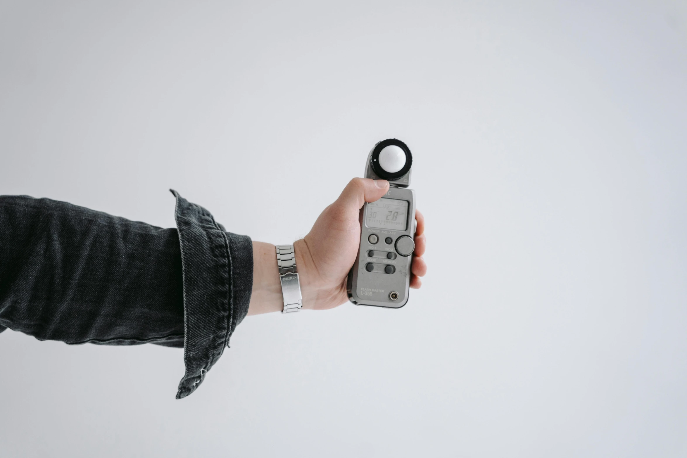 a person holding a remote control in their hand, by Matthias Stom, trending on pexels, minimalism, rolleiflex tlr, light grey mist, ring - flash, dial