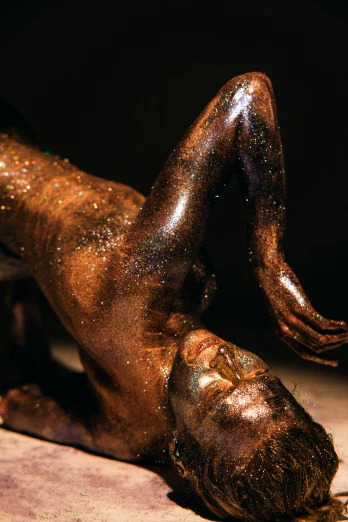a statue of a woman laying on the ground, a surrealist sculpture, inspired by Hedi Xandt, glowing glittery dust in the air, brown skin, close-up on legs, taken in 1 9 9 7